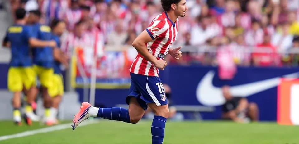 Player in Atletico Madrid kit running on pitch