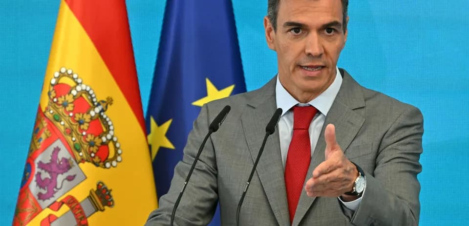 Man speaking at podium with Spanish and EU flags