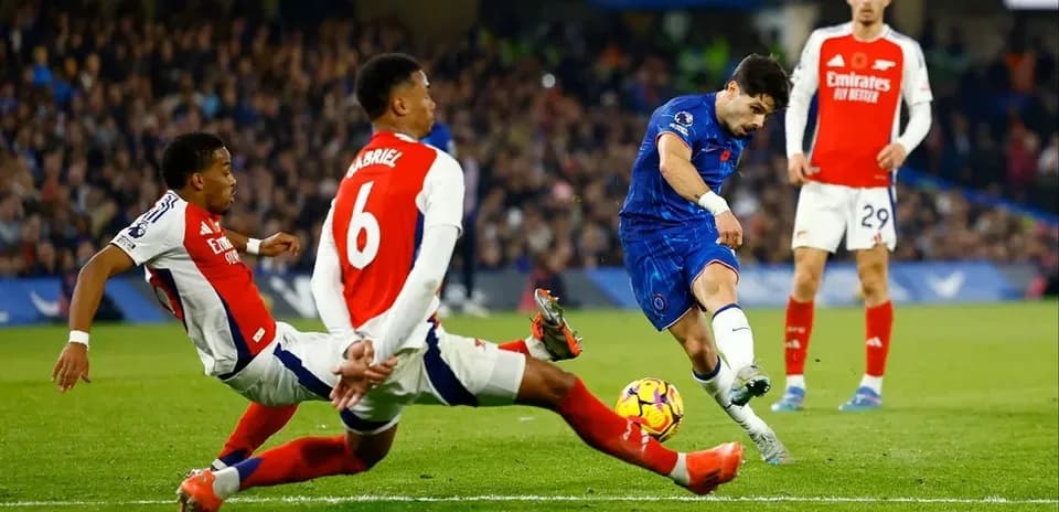 Chelsea player shooting while two Arsenal defenders challenge