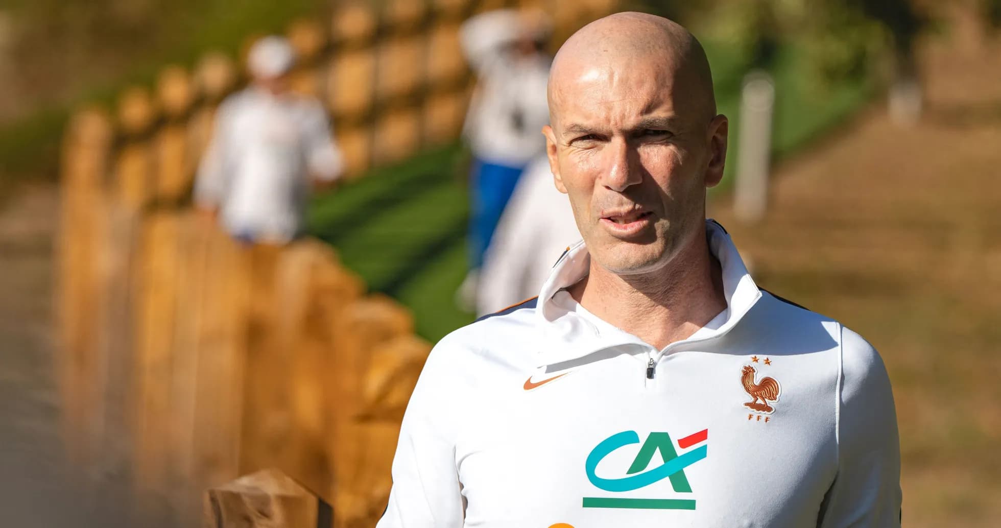 Coach walking near training ground with team in background