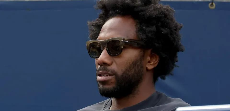 Man wearing sunglasses sitting on bleachers