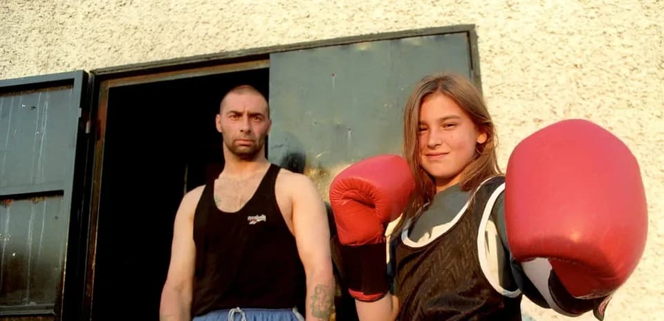 Young girl in boxing gloves with trainer outdoors