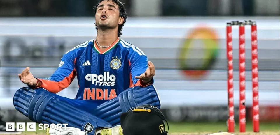 Cricketer in blue kit sitting behind stumps