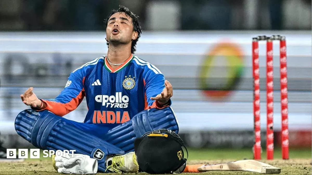 Cricketer in blue kit sitting behind stumps