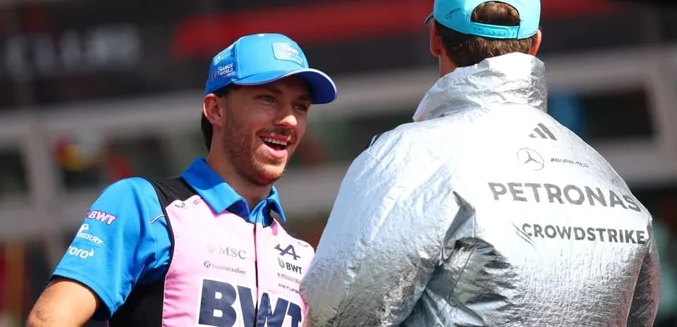 Two Formula 1 drivers conversing in team gear