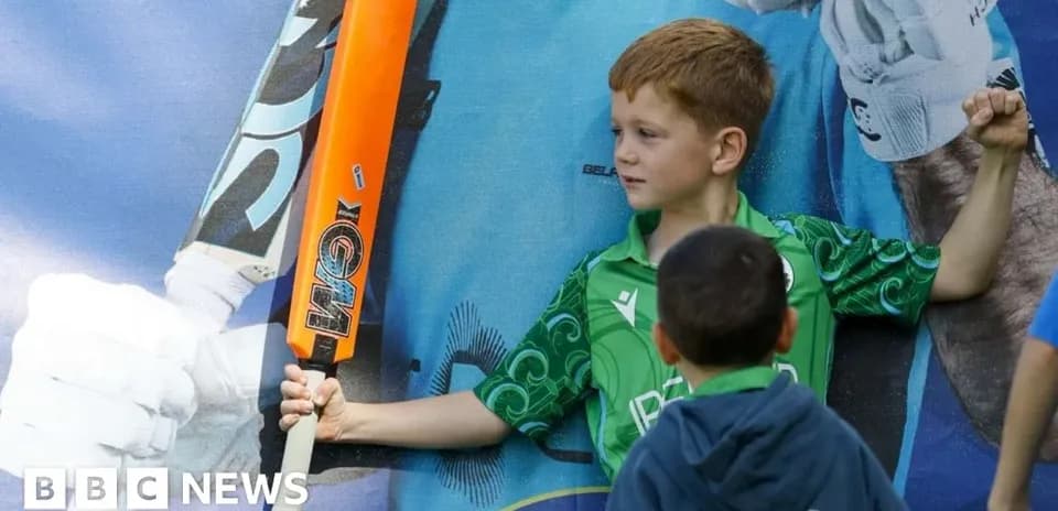 Child posing with cricket bat near poster