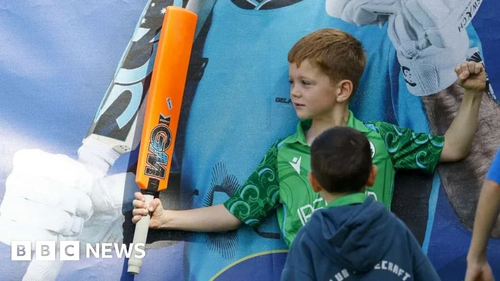Child posing with cricket bat near poster