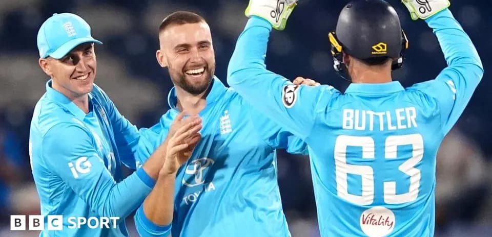 Three England players celebrating a wicket in cricket