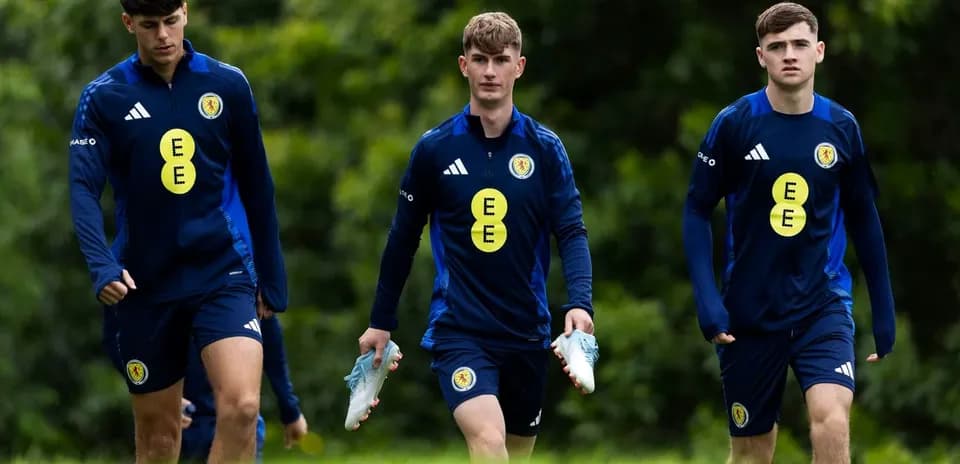 Three players walking in training kits with football boots