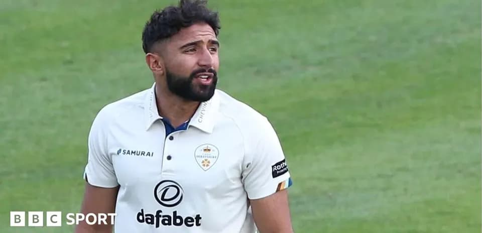 Cricketer wearing white kit on field during match