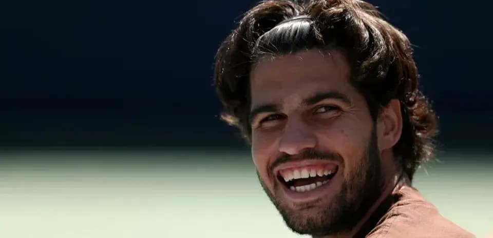 Smiling tennis player sitting on the court
