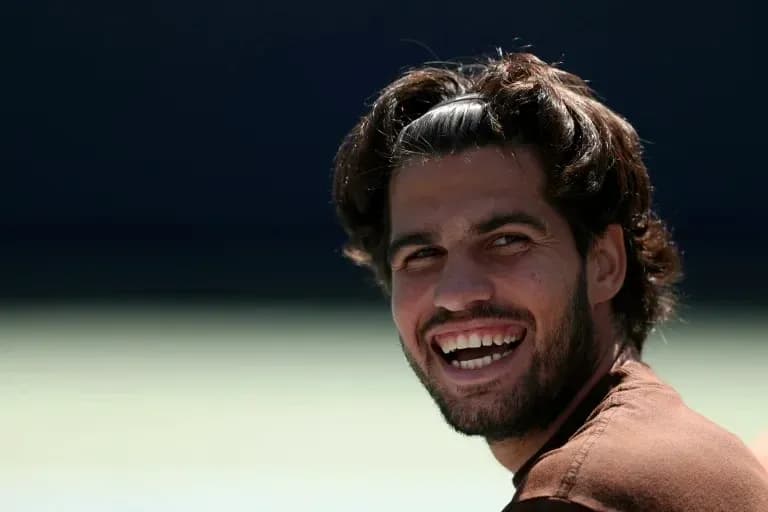 Smiling tennis player sitting on the court