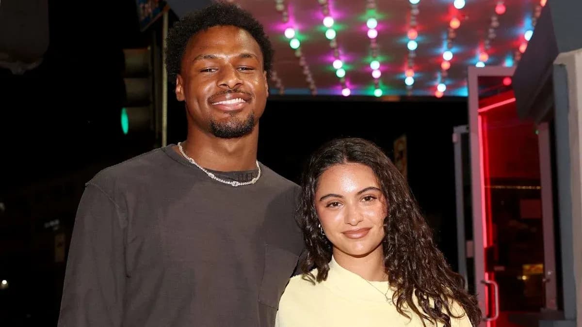Two individuals posing together under colorful lights