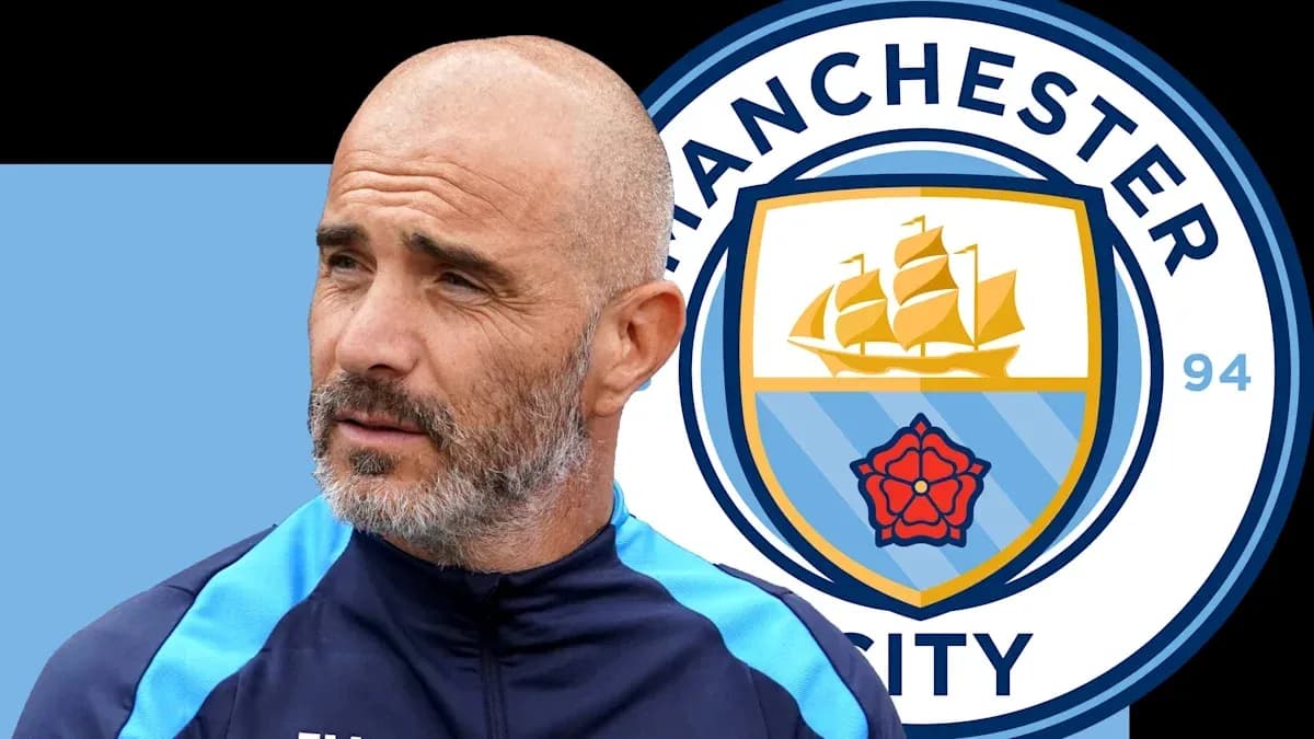 Coach standing next to Manchester City logo backdrop