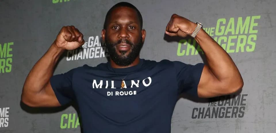 Man flexing muscles at promotional event backdrop