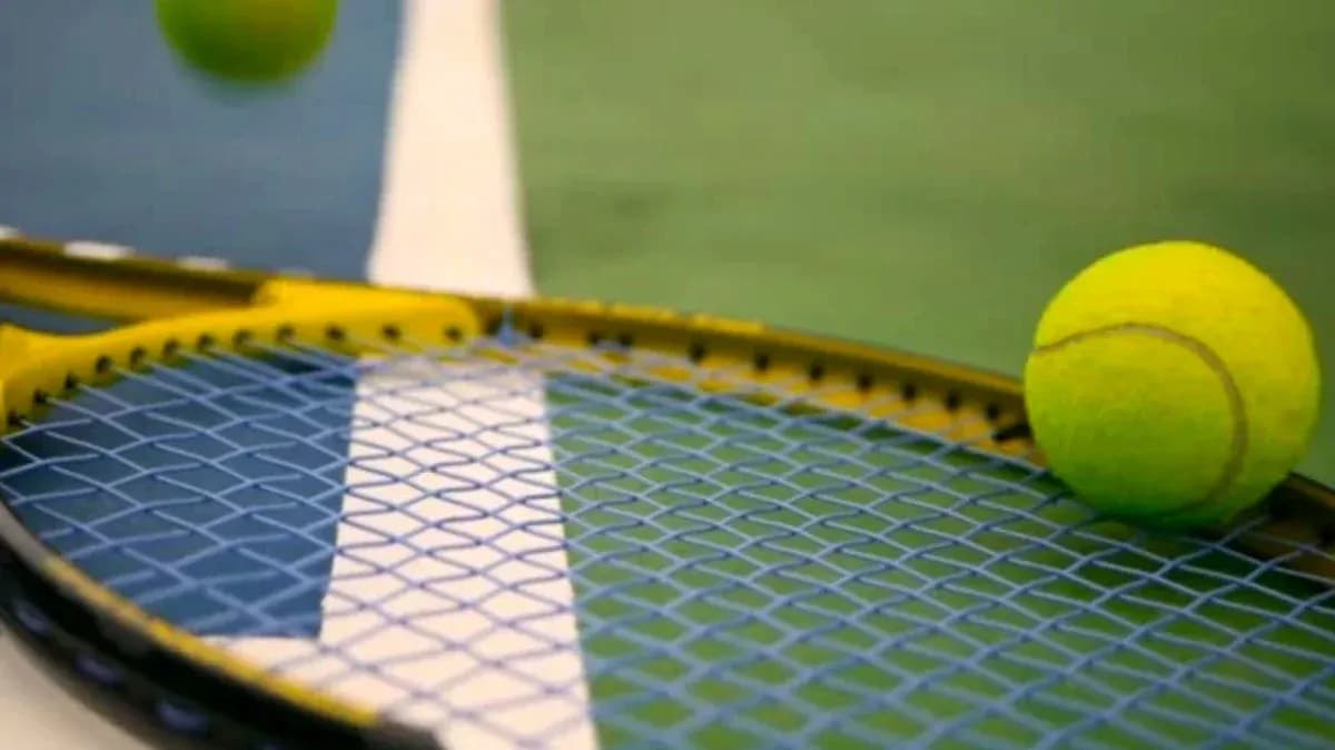 Tennis ball resting on a racket's strings