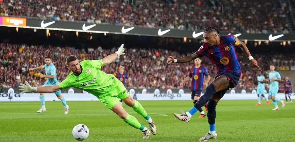 Barcelona player shooting past diving goalkeeper during match