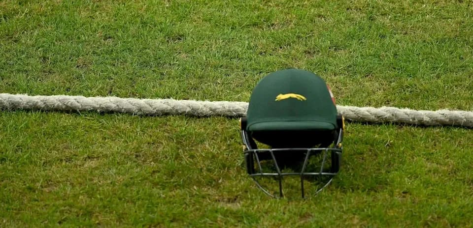 Cricket helmet resting on grass near boundary rope