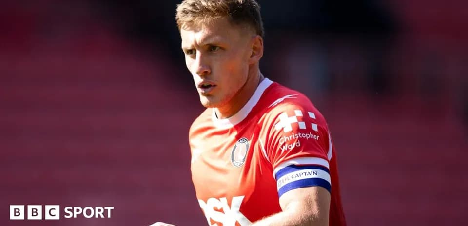 Player in red jersey with captain armband on pitch