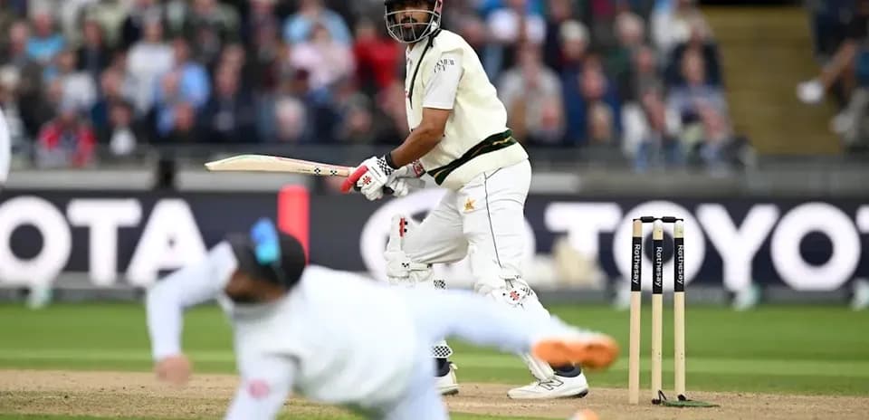 Batsman playing shot while fielder dives in cricket match