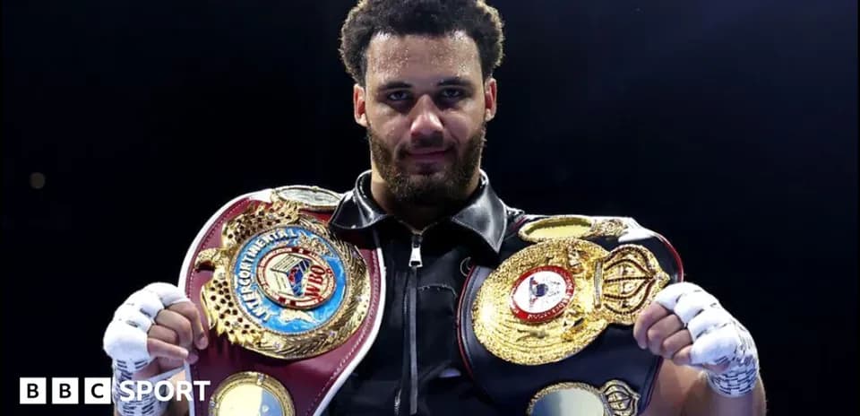 Boxer holding championship belts in the ring