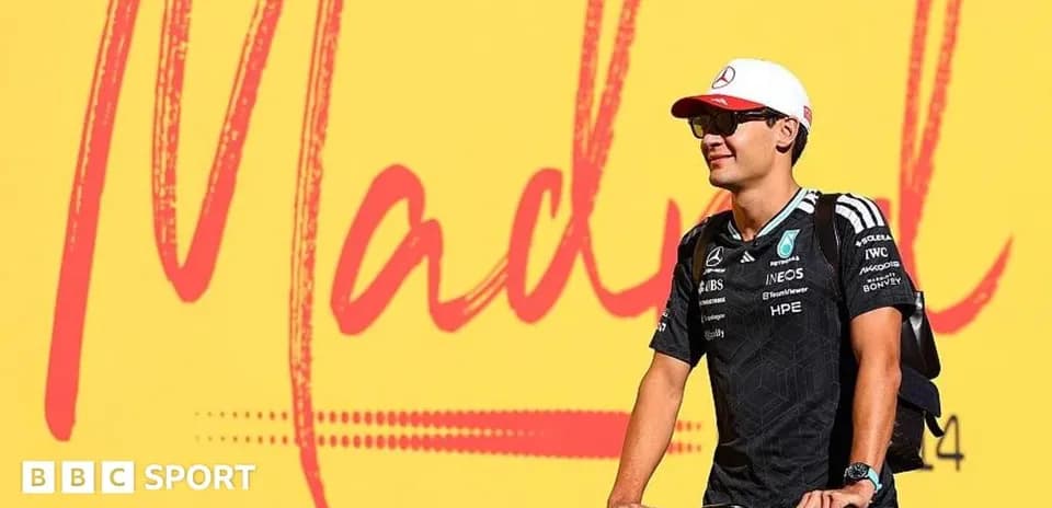 Racing driver on bicycle in front of mural