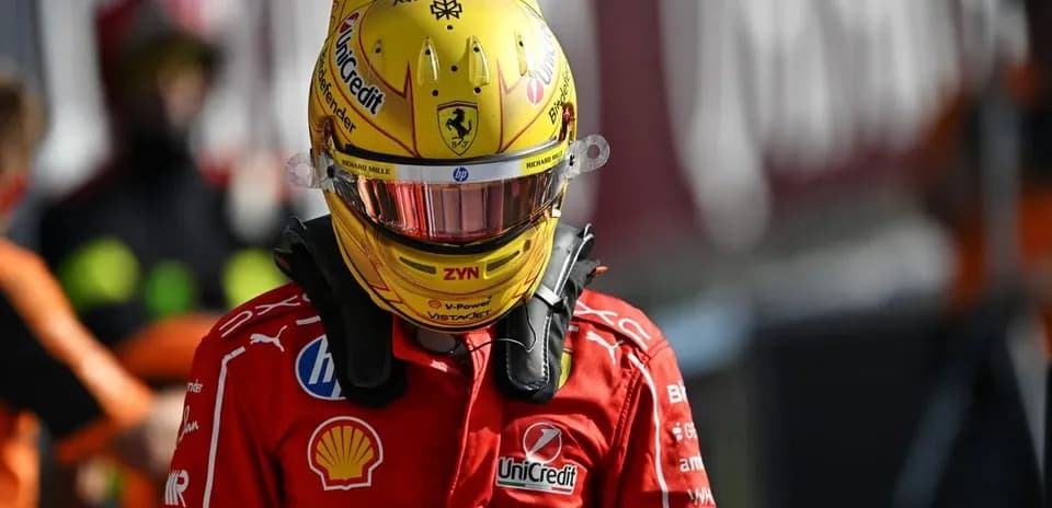 Driver in Ferrari suit wearing helmet on pit lane