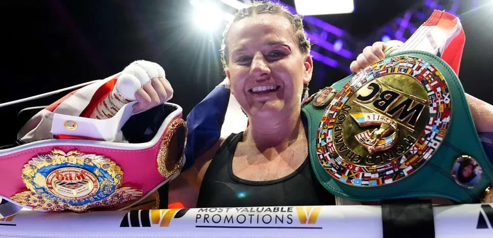 Boxer celebrating with championship belts in ring
