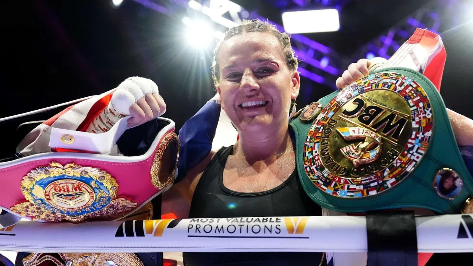 Boxer celebrating with championship belts in ring