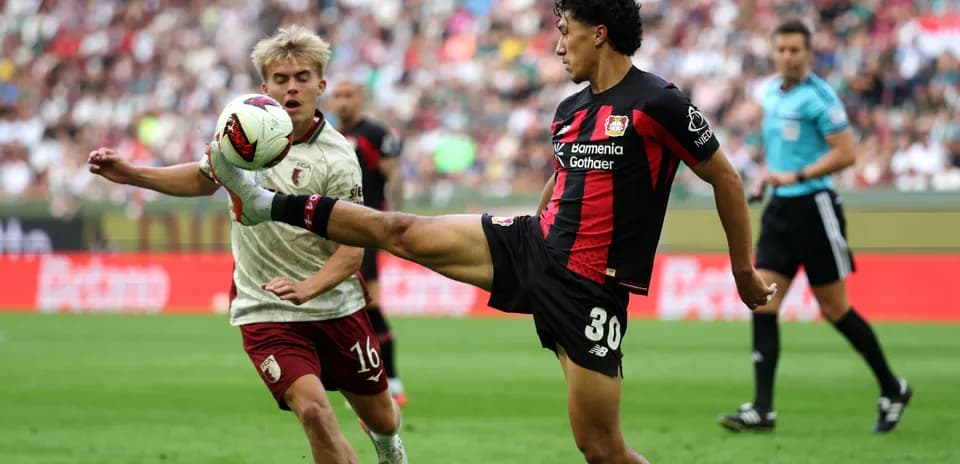 Player kicking ball while opponent attempts to block