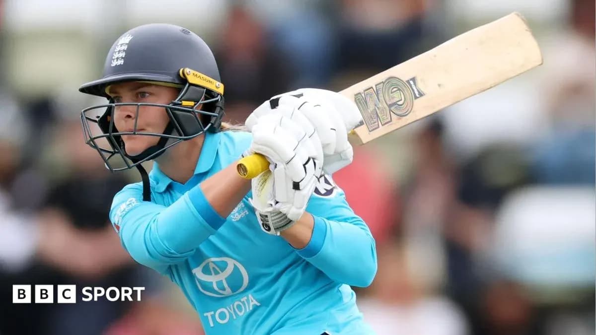 Cricketer batting during a match in blue uniform