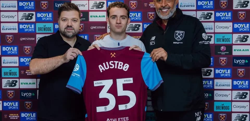 Player holding jersey with two officials at signing event