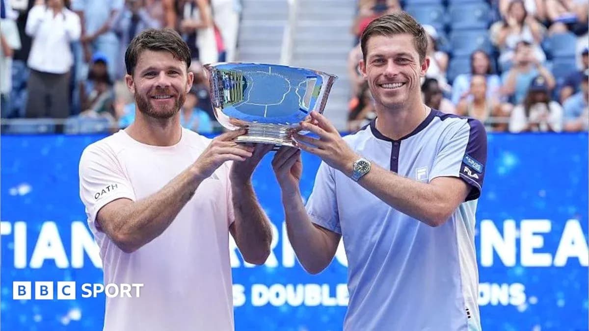 Two tennis players holding a trophy on court