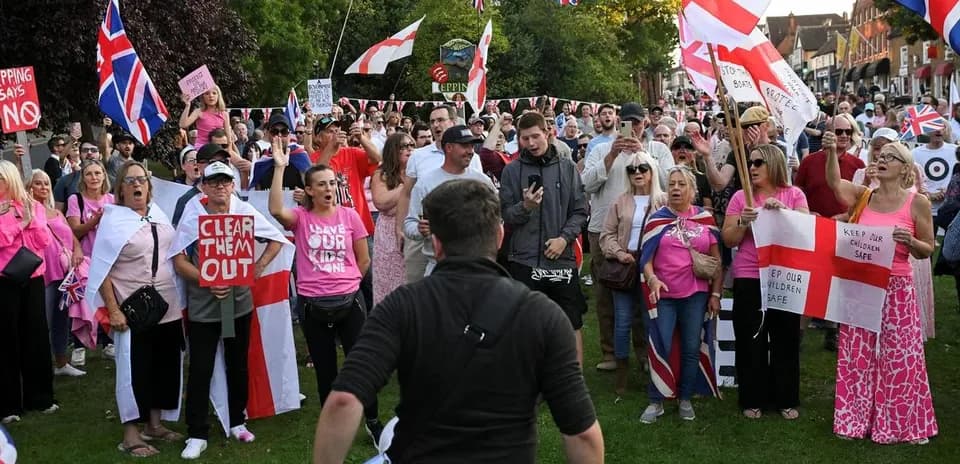 Crowd protesting with flags and signs in park