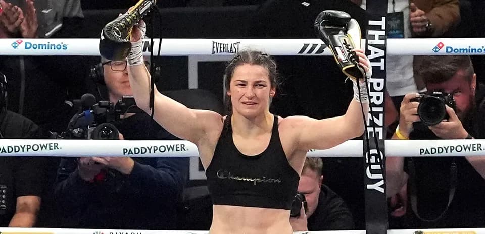 Boxer celebrating victory with championship belts raised