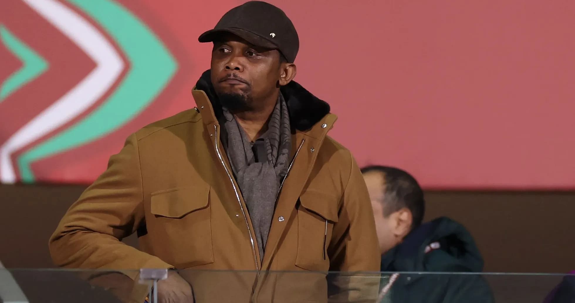 Man in brown jacket observing event from stands