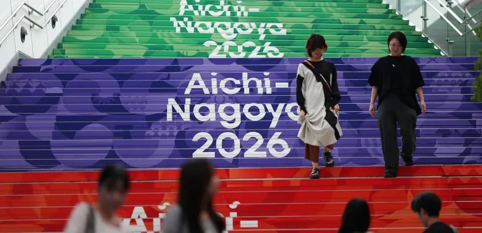 People walking down colorful stairs labeled Aichi-Nagoya 2026