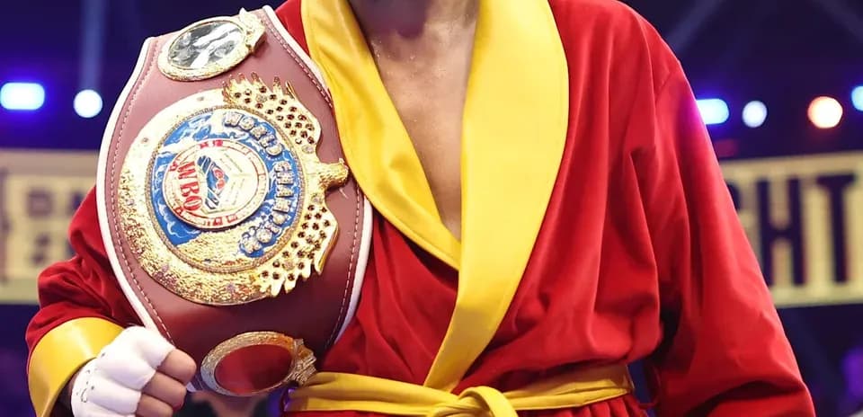 Boxer wearing red robe holding championship belt