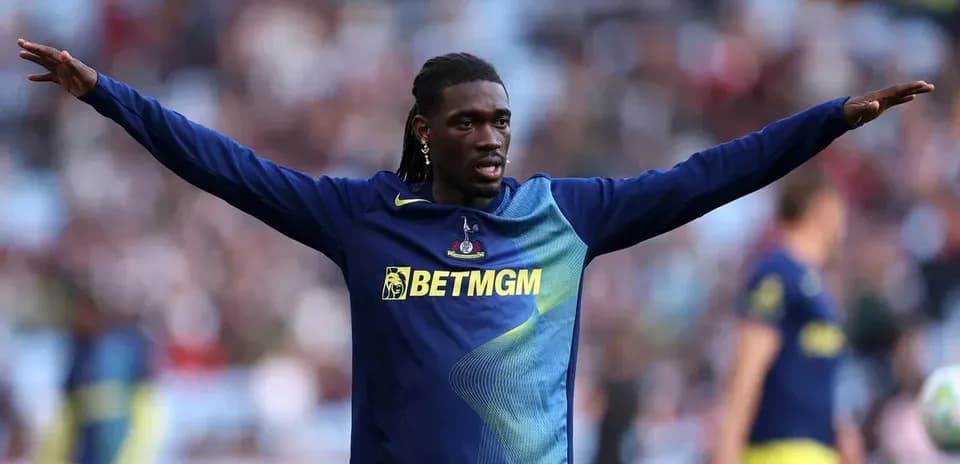 Player warming up with arms outstretched on pitch