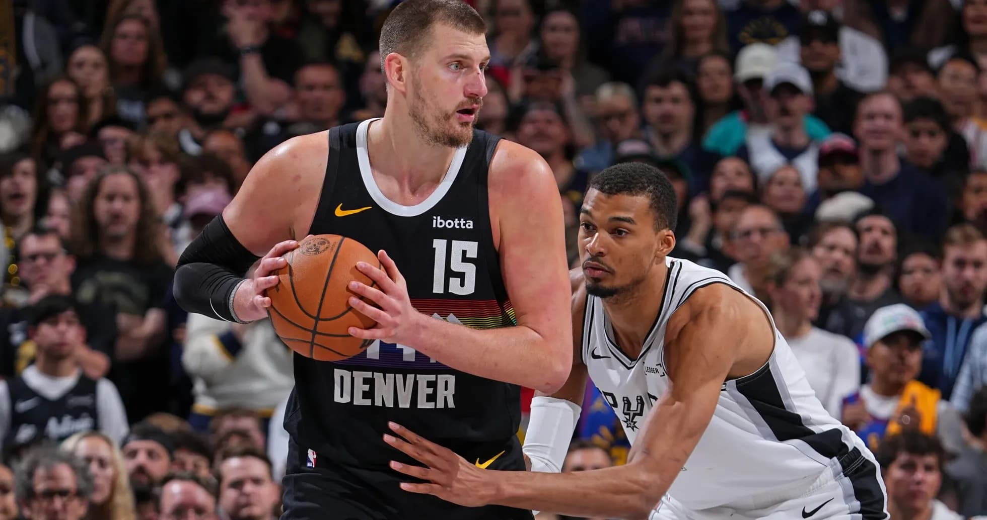 Nikola Jokić holding the ball, defended by player