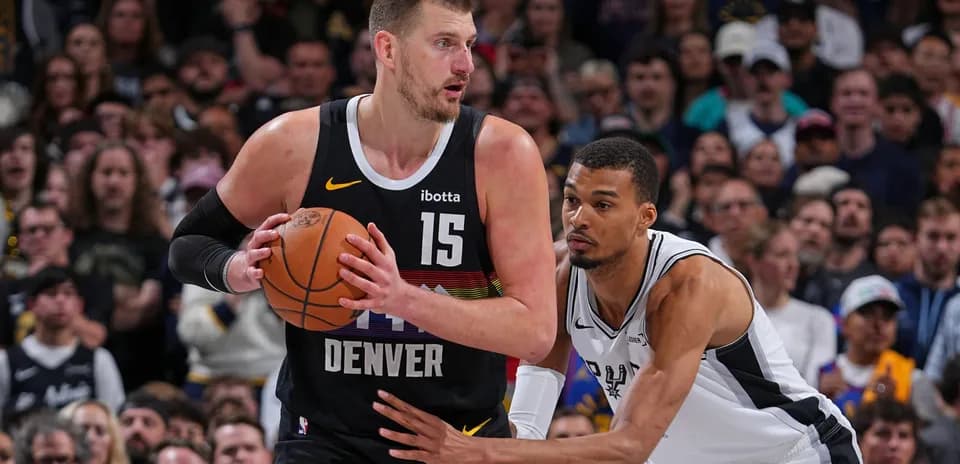 Nikola Jokić holding the ball, defended by player