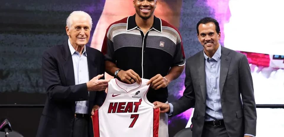 Three people at a press conference holding a jersey