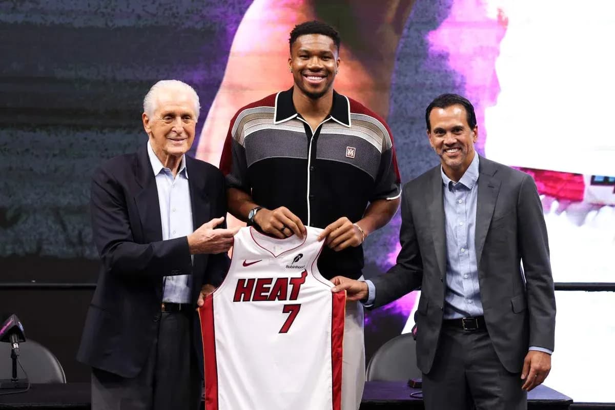 Three people at a press conference holding a jersey
