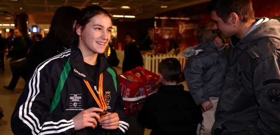 Athlete holding medal in airport with crowd