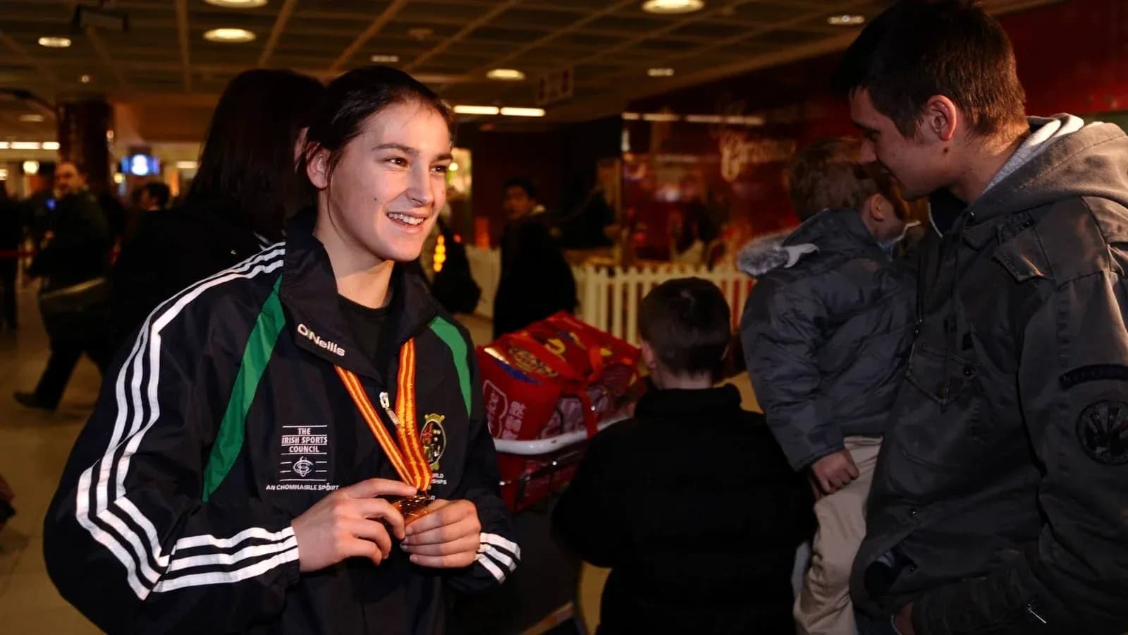 Athlete holding medal in airport with crowd