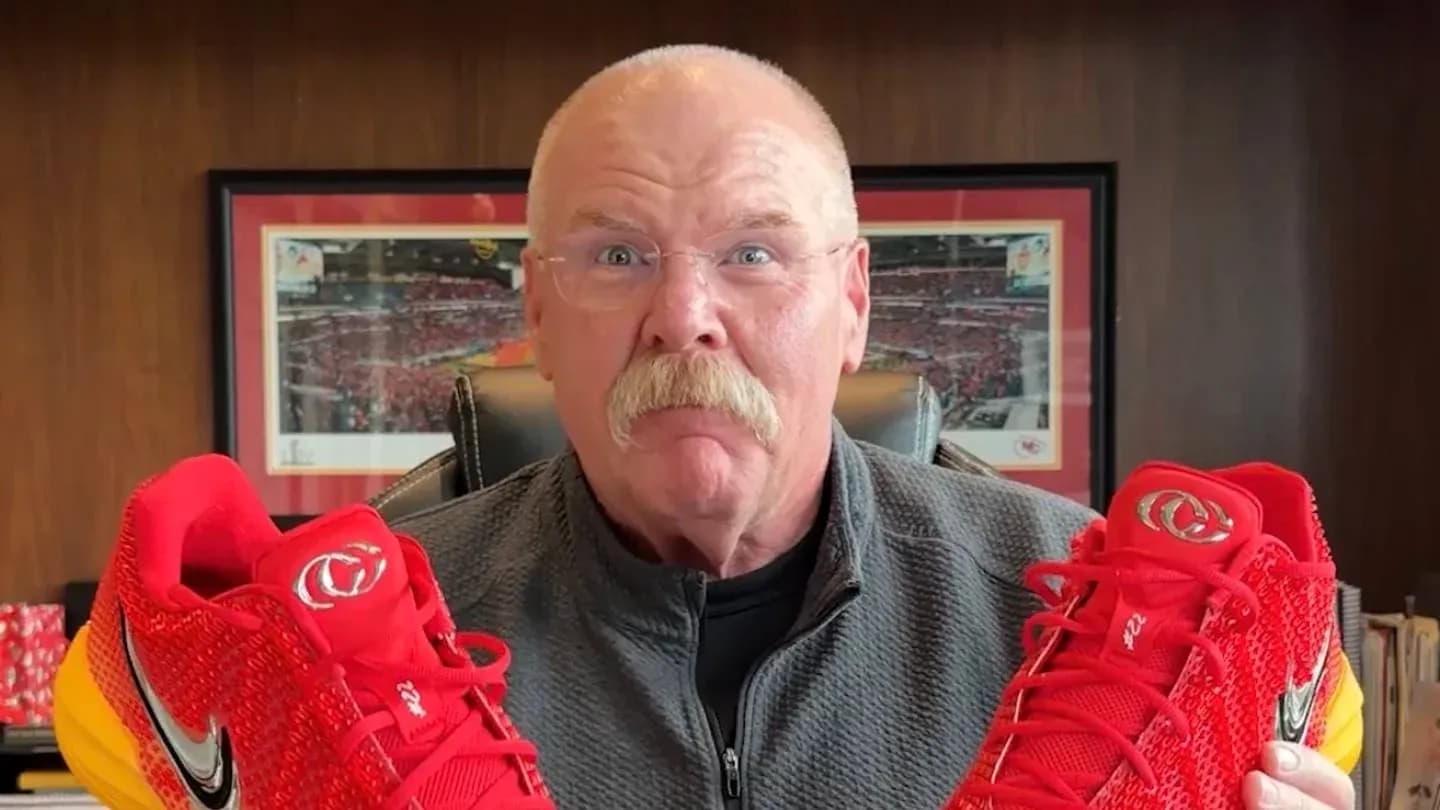 Person holding red sports shoes with yellow soles