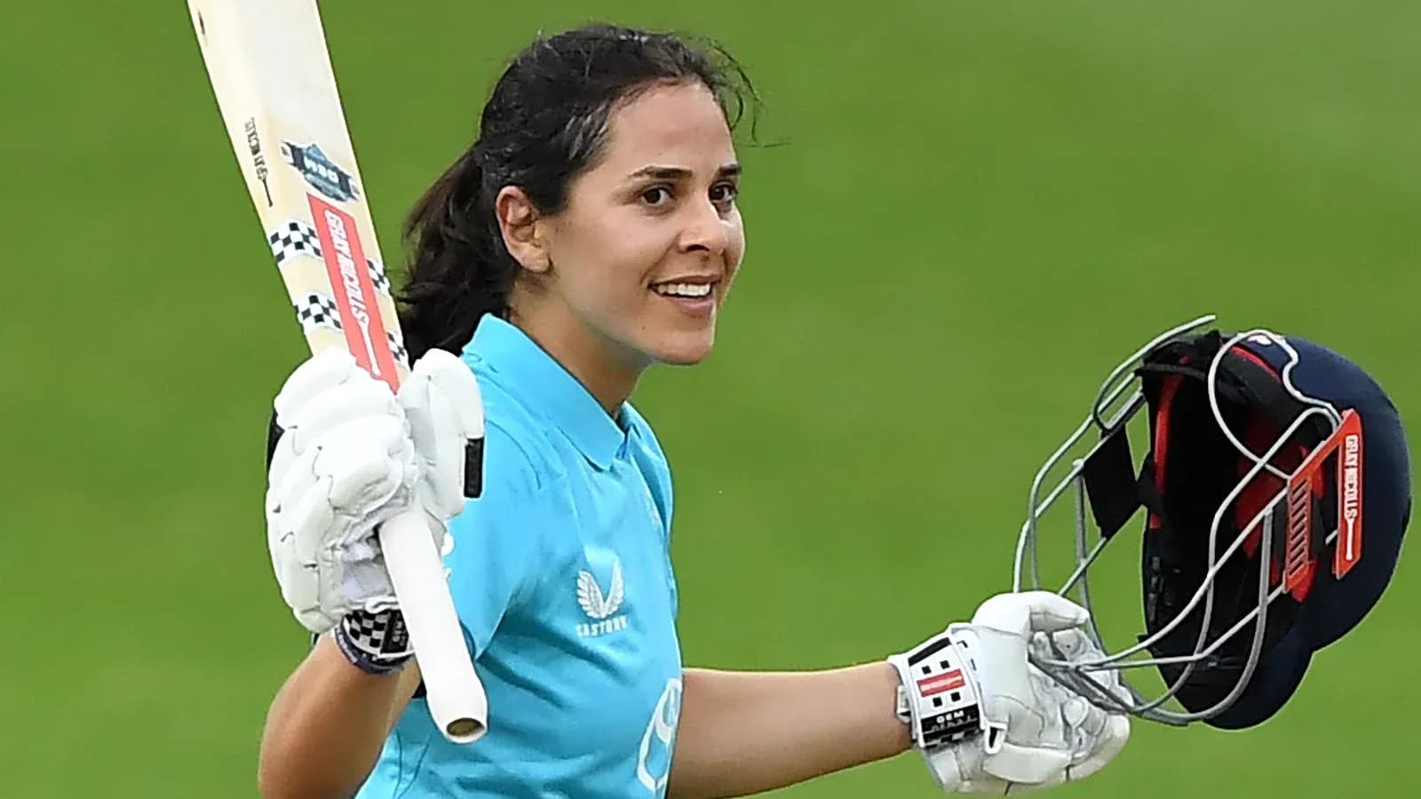 Female cricketer celebrating with bat and helmet Female cricketer celebrating with bat and helmet