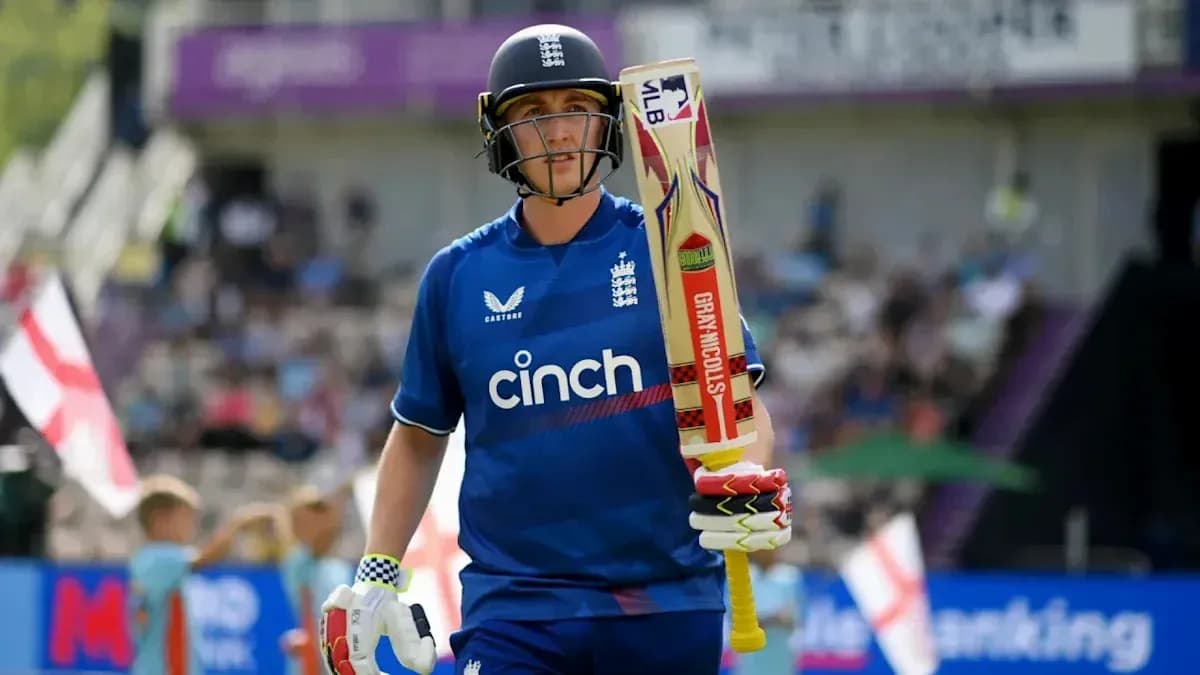 Cricketer walking off field with bat in hand Cricketer walking off field with bat in hand