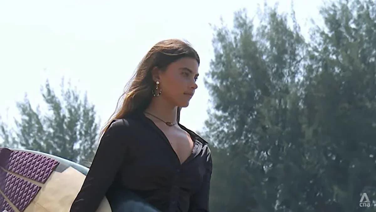 Surfer holding a board on beach path Surfer holding a board on beach path