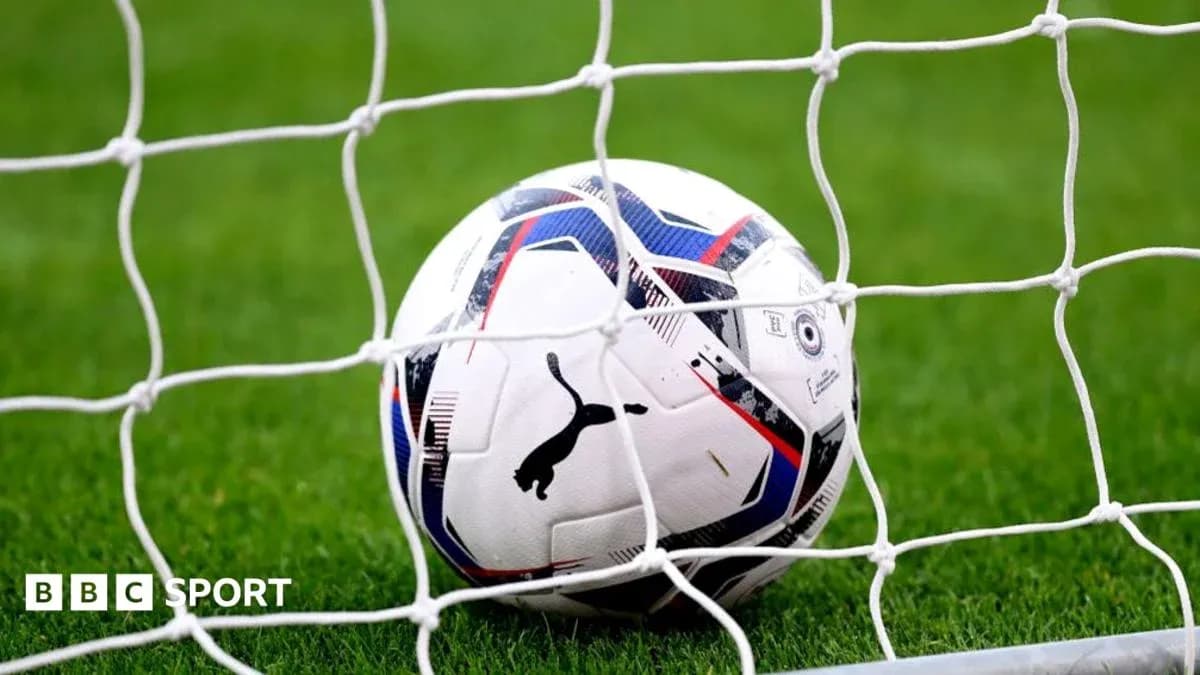 Football resting in goal net on grassy field Football resting in goal net on grassy field